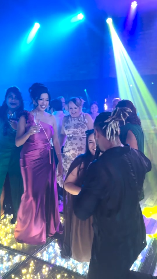 Banda Action se apresentando ao vivo com a pista de dança cheia sob luzes azuis